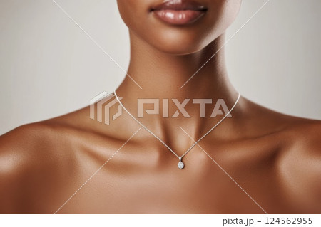 Elegant model showcases stylish silver necklace against minimalist backdrop with charm 124562955