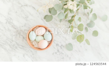 Minimalist Easter centerpiece featuring pastel Easter eggs on marble countertop with eucalyptus leaves for a stylish celebration 124563544