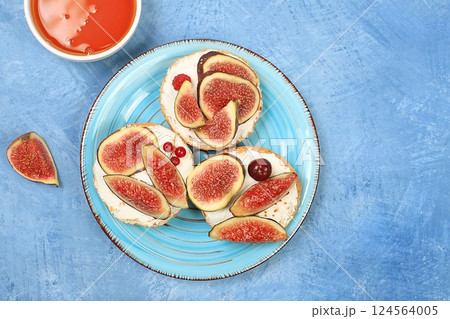 Ricotta,figs and bruschetta with honey on blue marble.Fresh sandwiches and toast with cream cheese,sliced figs,honey and cherries.Healthy breakfast with ingredients,lunch or dessert,diet food 124564005