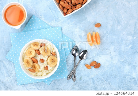 Useful breakfast with ingredients, flat lay, rice pudding with bananas, honey and almonds on a sunny table. Healthy and natural food concept, lifestyle, food for children, selective focus 124564314