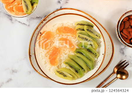 Rice pudding with kiwi, honey, tangerines and almonds. Healthy breakfast with ingredients, flat lay, Healthy and natural food concept, lifestyle, food for children 124564324
