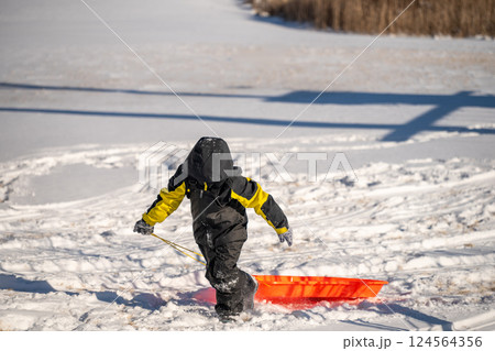 Child pulling a sled up a snow covered hill covered with tracks Child pulling a sled up a snow covered hill covered with tracks 124564356