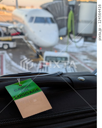 Gate check luggage tag on a roller suitcase in an airport. Gate check luggage tag on a roller suitcase in an airport. 124564416