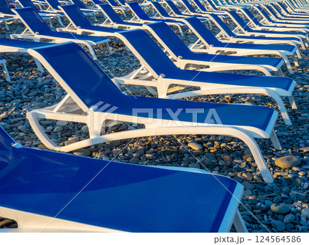 Beach chairs. Lots of empty sunbeds on the pebbles. The concept of commerce on the beach. Sunbed rental at the resort.  Rest of people on the sea. 124564586