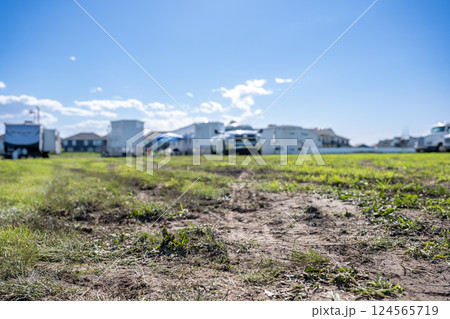 Selective focus on mud and torn up grass in the foreground of a dirt parking lot 124565719