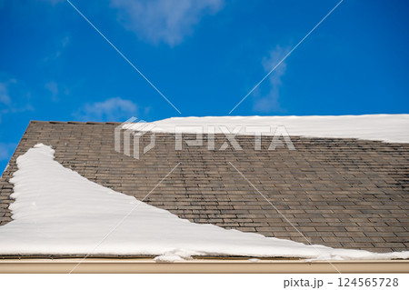 Snow and ice along a residential roof gutter forming a dam in the winter. Snow and ice along a residential roof gutter forming a dam in the winter. 124565728