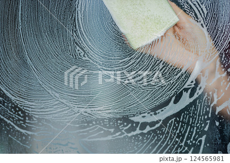 Сlose up of glass surface covered in soapy foam with sponge wiping it clean,highlighting texture Сlose up of glass surface covered in soapy foam with sponge wiping it clean,highlighting texture 124565981