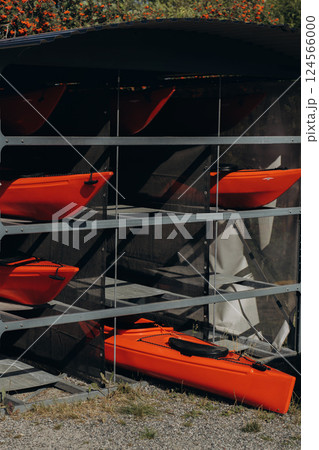 Collection of vibrant red plastic recreational canoe and kayaks stored storage rack, front view Collection of vibrant red plastic recreational canoe and kayaks stored storage rack, front view 124566000