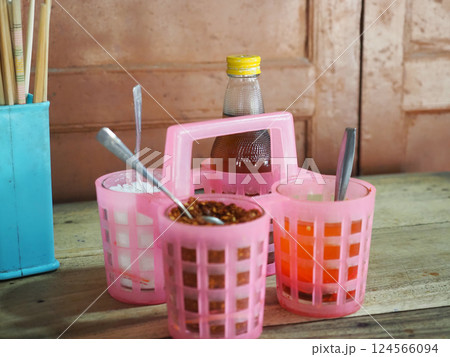 A vibrant display of colorful condiments in pink plastic baskets, showcasing variety of flavors and textures, perfect for enhancing meals 124566094