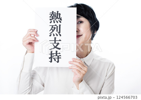 熱烈支持と書かれた紙を掲げチラ見する中年女性 124566703