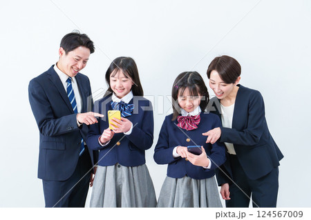 スマートフォンを使う女の子　見守る両親 124567009