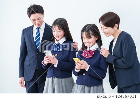 スマートフォンを使う女の子　見守る両親 124567011