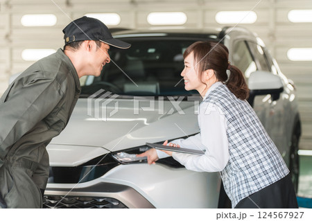 自動車の前で会話する自動車整備士の男性と事務服姿の女性フロント,事務員 124567927