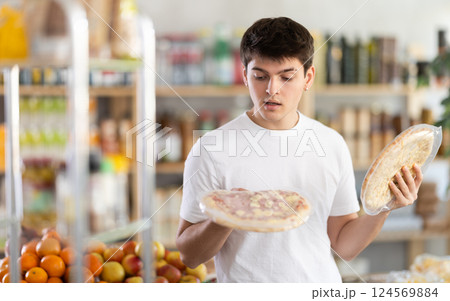 European guy looks at product and shop around, choose and buy pizza with different filling in shop European guy looks at product and shop around, choose and buy pizza with different filling in shop 124569884