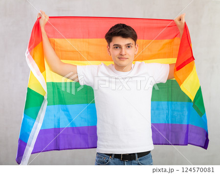 Smiling young guy holding LGBT flag 124570081