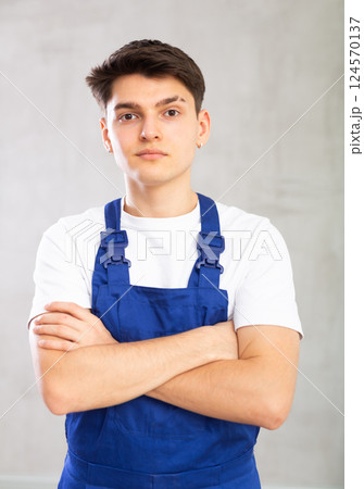 Portrait of positive smiling guy in blue protective overalls Portrait of positive smiling guy in blue protective overalls 124570137
