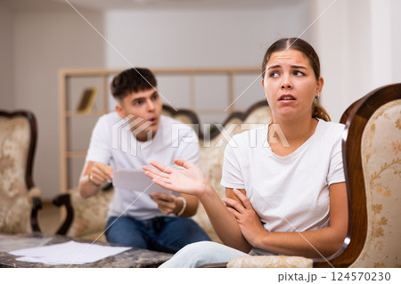 Angry young husband with documents swears at his wife Angry young husband with documents swears at his wife 124570230