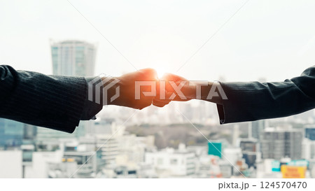 都市を背景にグータッチするビジネスパーソンのグループ 都市を背景にグータッチするビジネスパーソンのグループ 124570470