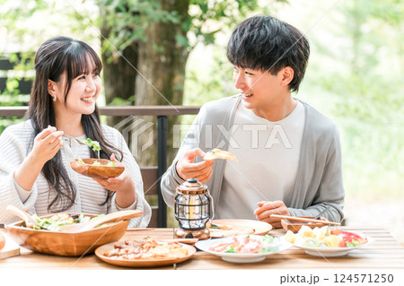 ウッドデッキ・テラス席・バルコニー席で食事するカップル・夫婦(グランピング・ベランピング) ウッドデッキ・テラス席・バルコニー席で食事するカップル・夫婦(グランピング・ベランピング) 124571250