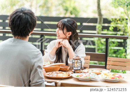 ウッドデッキ・テラス席・バルコニー席で食事するカップル・夫婦（グランピング・ベランピング） 124571255
