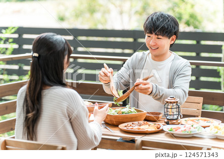 ウッドデッキ・テラス席・バルコニー席で食事するカップル・夫婦（グランピング・ベランピング） 124571343