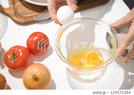 ボールに割った新鮮な卵を持つミドル女性の手 ボールに割った新鮮な卵を持つミドル女性の手 124571364