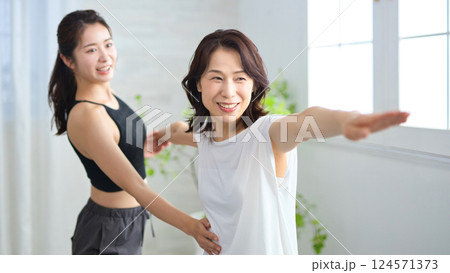 ヨガインストラクターにレッスンを受けるミドル女性 124571373