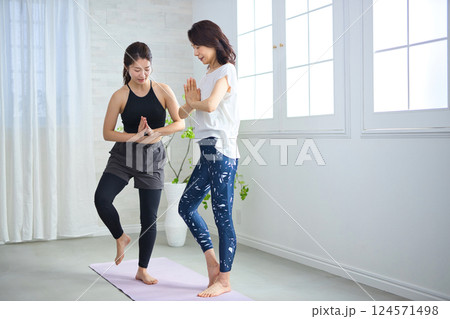 ヨガインストラクターにレッスンを受けるミドル女性 124571498