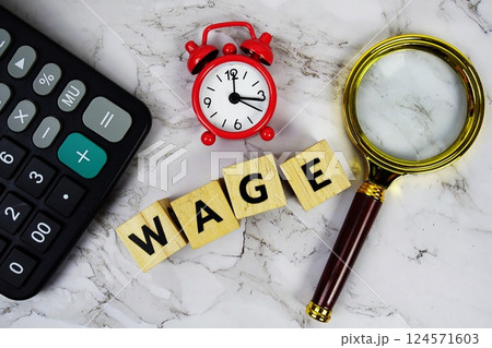 Wage with wooden blocks alphabet letters and Magnifying glass and calculator on marble background Wage with wooden blocks alphabet letters and Magnifying glass and calculator on marble background 124571603