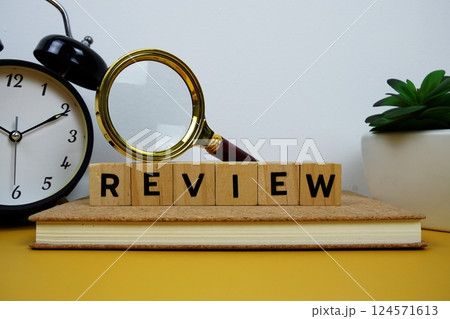 Magnifying glass and alarm clock with wooden blocks alphabet letters REVIEW text message on yellow background Magnifying glass and alarm clock with wooden blocks alphabet letters REVIEW text message on yellow background 124571613