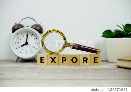 Magnifying glass and alarm clock with wooden blocks alphabet letters EXPORE text message on wooden background Magnifying glass and alarm clock with wooden blocks alphabet letters EXPORE text message on wooden background 124571631