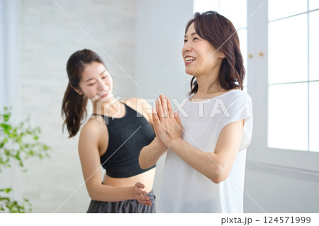ヨガインストラクターにレッスンを受けるミドル女性 124571999