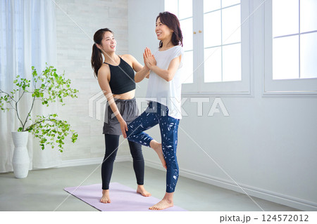 ヨガインストラクターにレッスンを受けるミドル女性 ヨガインストラクターにレッスンを受けるミドル女性 124572012