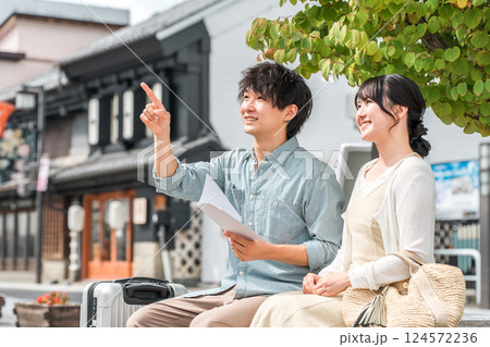 ガイドブックを見て国内旅行で街歩き・観光ツアーをする若い夫婦・カップル 124572236
