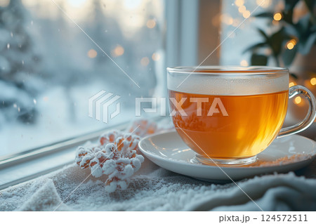 雪の窓辺に置かれた湯気立つガラスの紅茶カップ 124572511