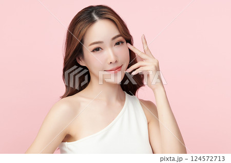 A beautiful young Asian woman with clean, fresh skin against a pink background. Skincare, facial treatment, cosmetology, beauty, and spa. An elegant portrait of an Asian woman. 124572713