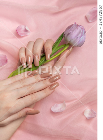 Woman hands with perfect nude manicure holding purple tulip on pink background Woman hands with perfect nude manicure holding purple tulip on pink background 124572967
