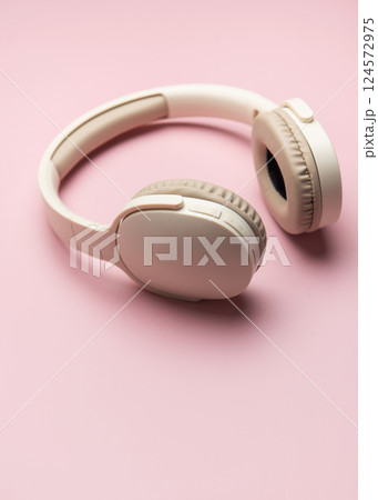 Modern wireless headphones lying on pink background 124572975