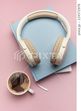 Wireless headphones resting on books with coffee nearby, embracing relaxation and productivity 124572976