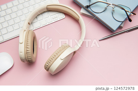 Wireless headphones, keyboard, computer mouse, eyeglasses, pen and notebooks on pink background Wireless headphones, keyboard, computer mouse, eyeglasses, pen and notebooks on pink background 124572978