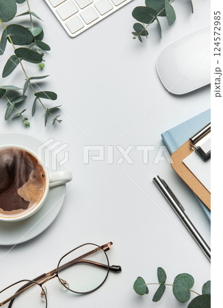 Eucalyptus branches, coffee, keyboard, and mouse framing white desk background 124572985