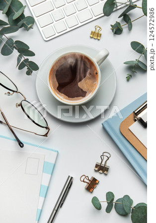 Eucalyptus, coffee cup, keyboard and stationery creating relaxing atmosphere on white table 124572986