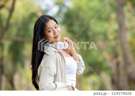A woman looking happily at her notebook as she figure something out while sitting on park sidewalk 124574026