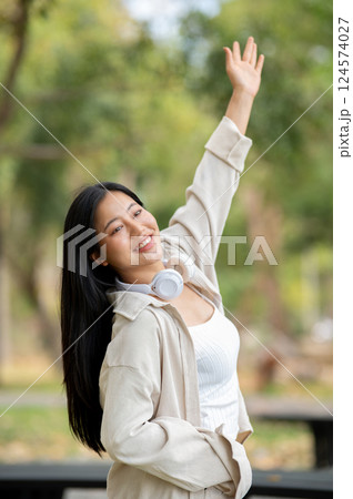 A woman looking happily at her notebook as she figure something out while sitting on park sidewalk 124574027