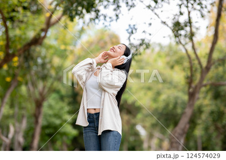 A woman looking happily at her notebook as she figure something out while sitting on park sidewalk 124574029