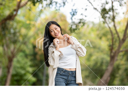 A woman looking happily at her notebook as she figure something out while sitting on park sidewalk A woman looking happily at her notebook as she figure something out while sitting on park sidewalk 124574030