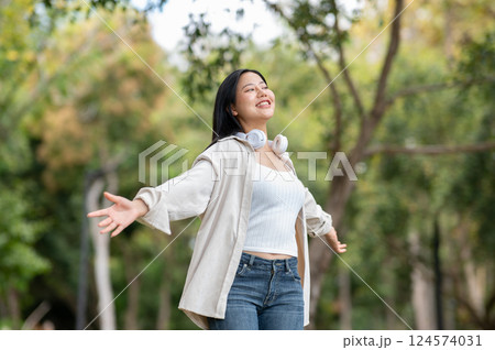 A woman looking happily at her notebook as she figure something out while sitting on park sidewalk 124574031