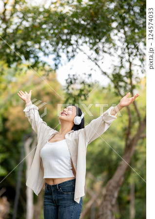 A woman looking happily at her notebook as she figure something out while sitting on park sidewalk 124574033