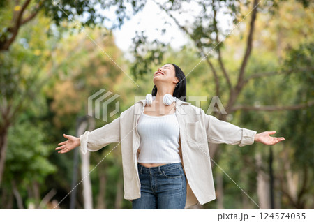 A woman looking happily at her notebook as she figure something out while sitting on park sidewalk 124574035