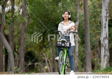 A woman looking happily at her notebook as she figure something out while sitting on park sidewalk 124574054